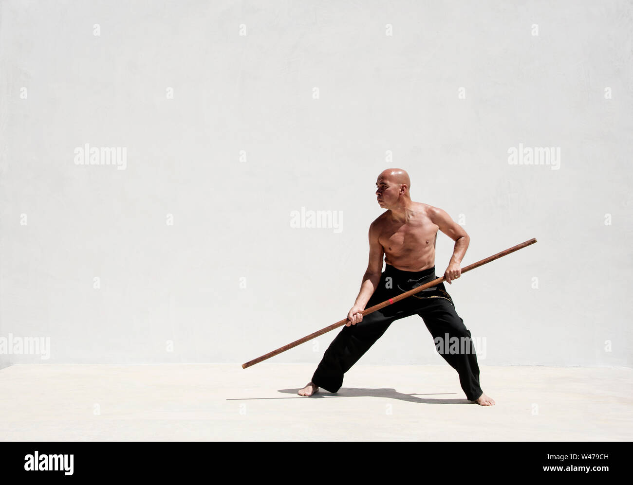 Black belt man practicing martial arts with a long stick Stock Photo Alamy
