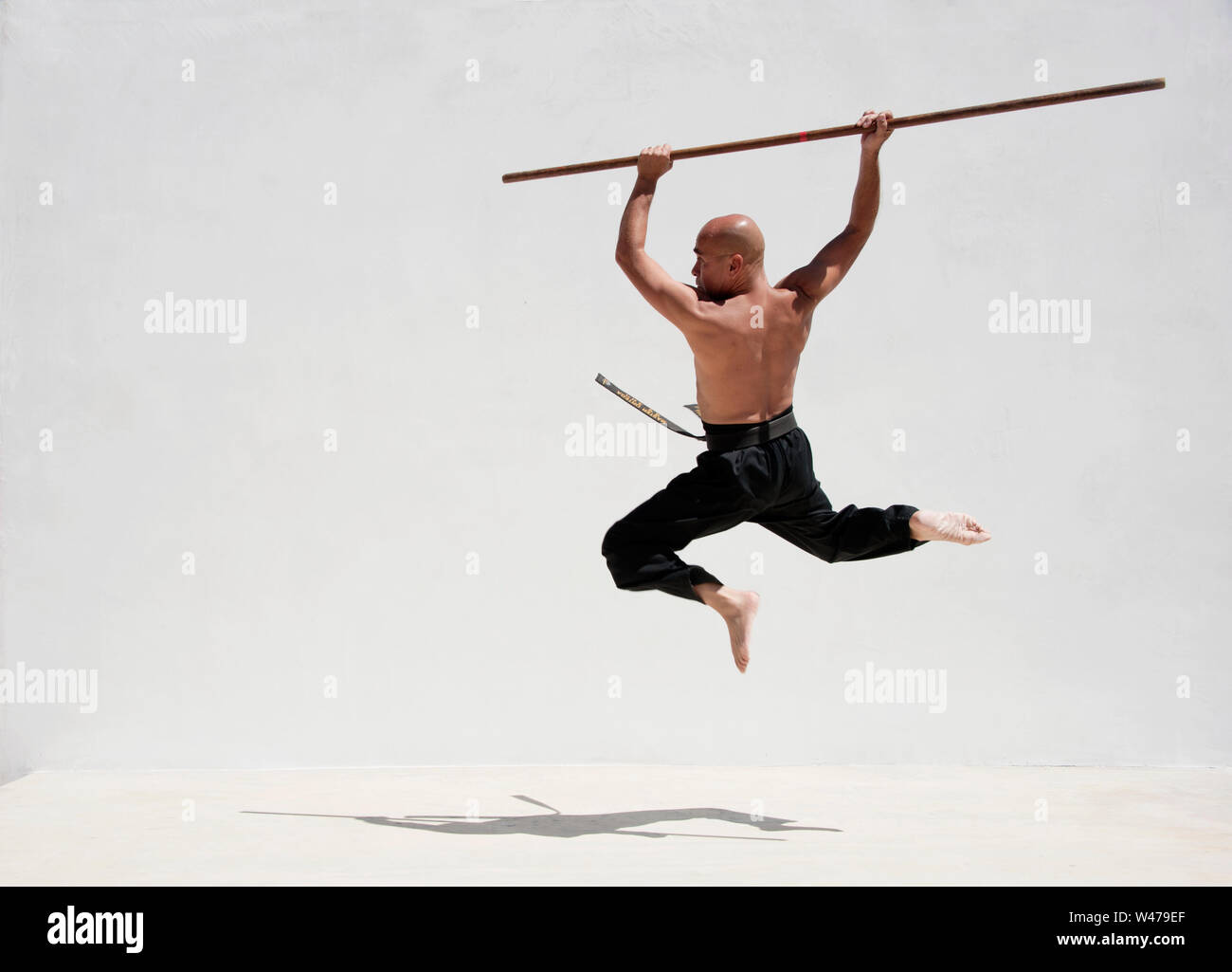 Black belt man practicing martial arts with a long stick Stock Photo Alamy