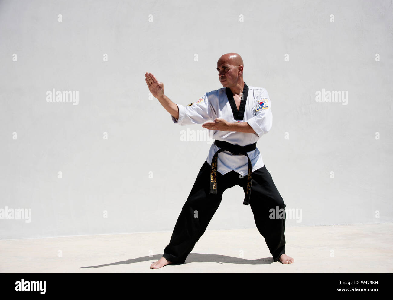 Black belt Sensei martial arts instructor demonstrating Taekwondo form. He is a master and instructor as designated by his uniform and form. Stock Photo