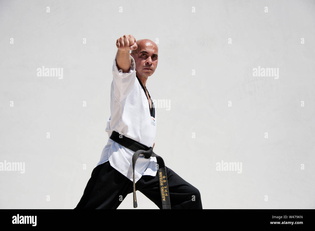 Black belt Sensei martial arts instructor demonstrating Taekwondo form. He is a master and instructor as designated by his uniform and form. Stock Photo