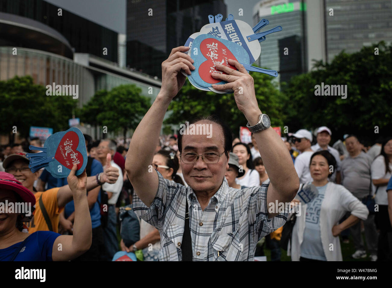 A man distributes fans with  Safeguard HK during pro-government  Safeguard Hong Kong rally at Tamar Park.Government supporters show up in number of tens of thousands in a pro-police rally, at Tamar Park.  Named Safeguard Hong Kong,  the demonstration was co-organized by 70 pro-Beijing figures and  was attended by local residents, mainland immigrants, members of ethnic minorities, as well as visitors from across the border. Stock Photo