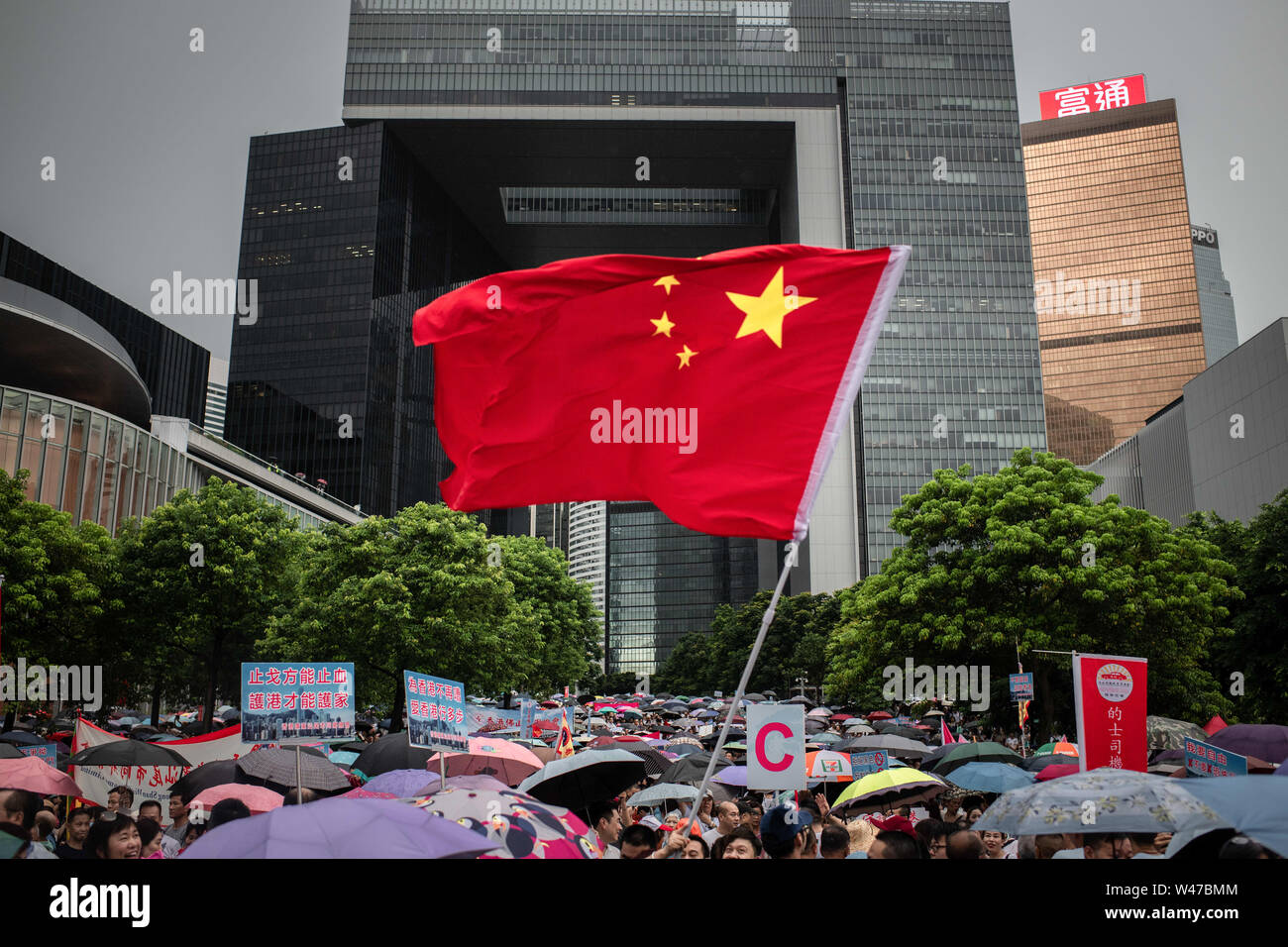 A Chinese flag flutters amid the umbrellas at pro-government Safeguard Hong Kong rally at Tamar Park.Government supporters show up in number of tens of thousands in a pro-police rally, at Tamar Park.  Named Safeguard Hong Kong,  the demonstration was co-organized by 70 pro-Beijing figures and  was attended by local residents, mainland immigrants, members of ethnic minorities, as well as visitors from across the border. Stock Photo
