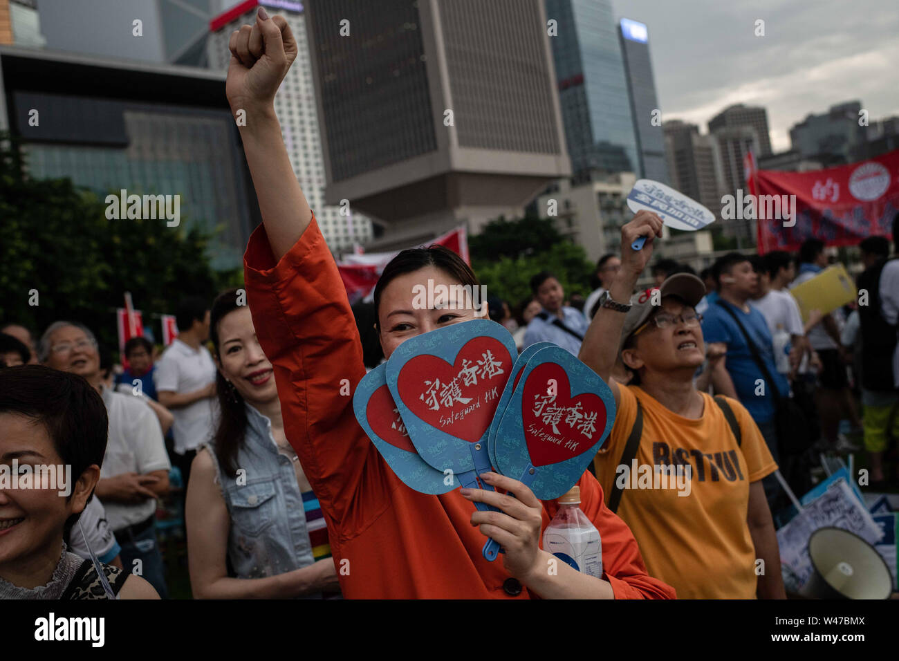 A woman distributes fans with  Safeguard HK during pro-government  Safeguard Hong Kong rally at Tamar Park.Government supporters show up in number of tens of thousands in a pro-police rally, at Tamar Park.  Named Safeguard Hong Kong,  the demonstration was co-organized by 70 pro-Beijing figures and  was attended by local residents, mainland immigrants, members of ethnic minorities, as well as visitors from across the border. Stock Photo