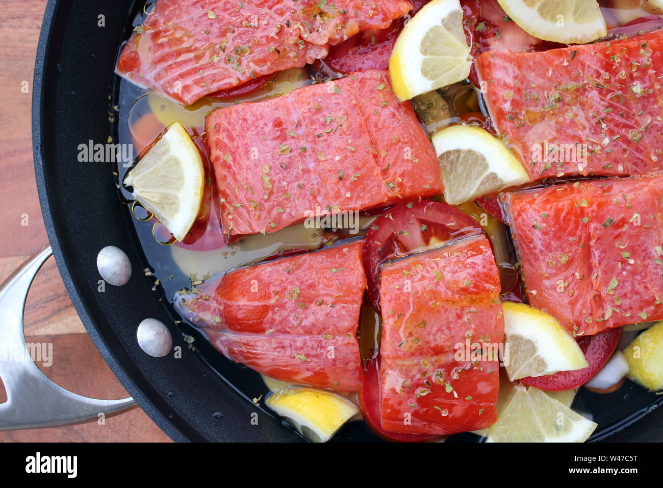 Poaching sockeye salmon fillets in water with vegetables and lemon Stock Photo