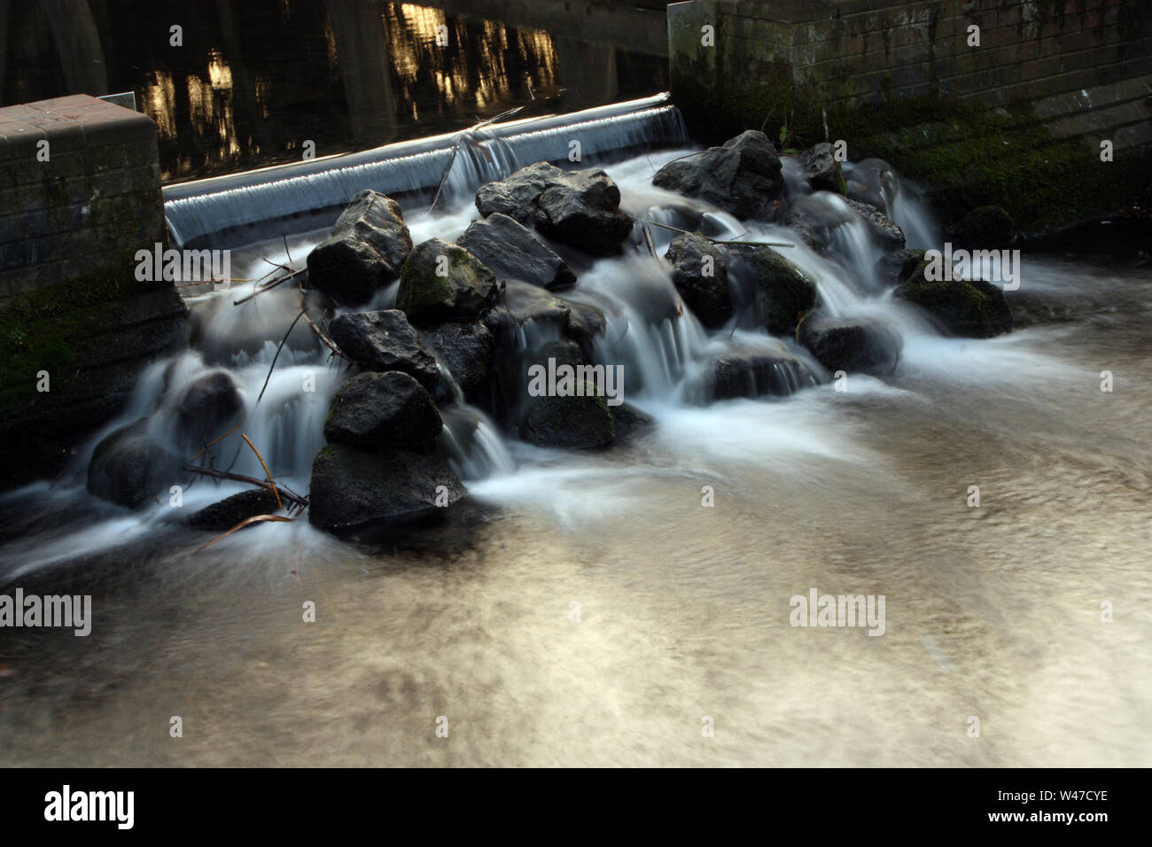 Slow exposure of water flowing over rocks at Carshalton Ponds, Sutton Stock Photo