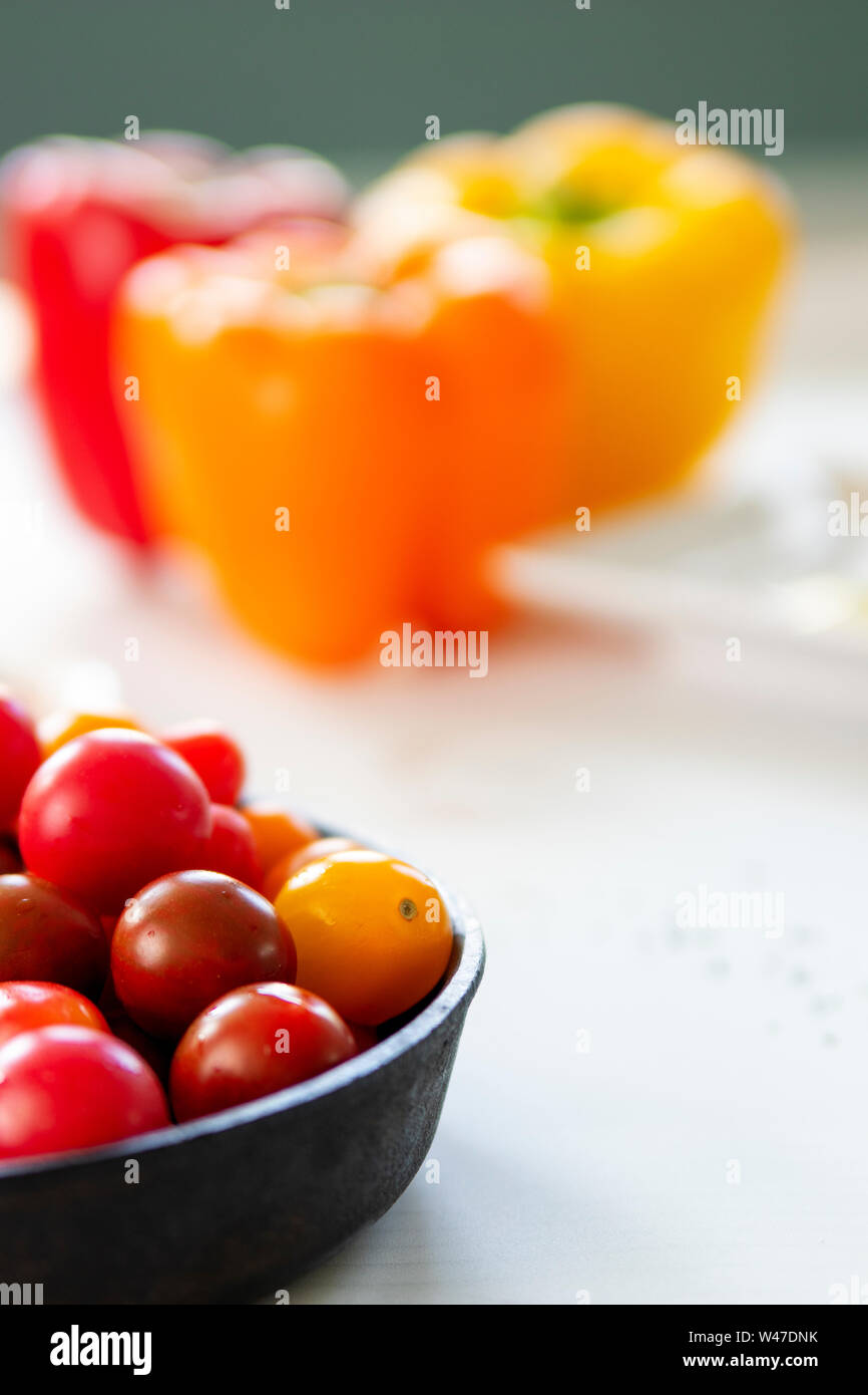 Cherry tomatoes with bell peppers out of focus in background Stock Photo