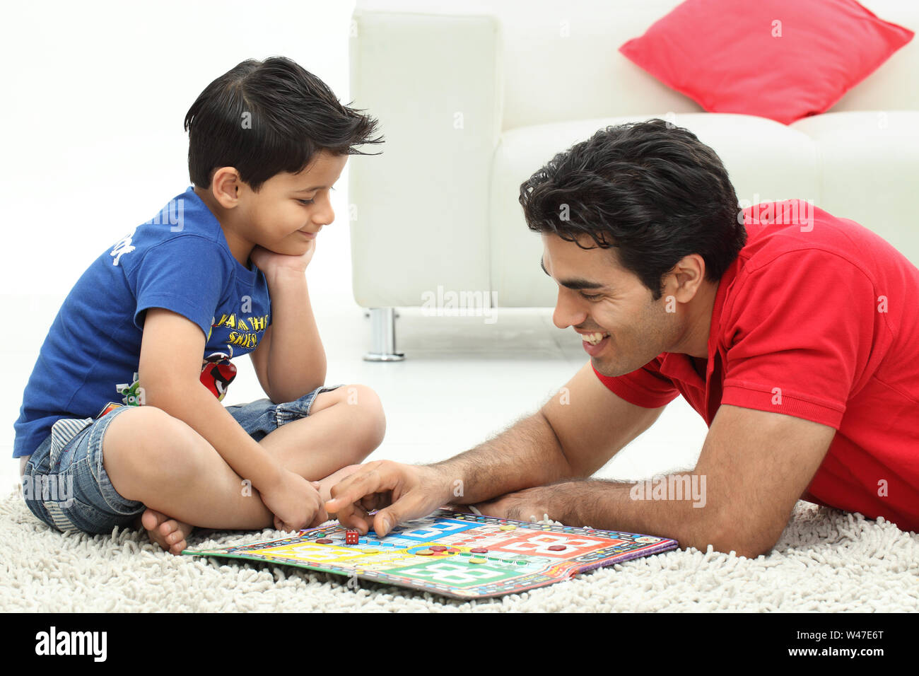 Boy playing Ludo with his father Stock Photo