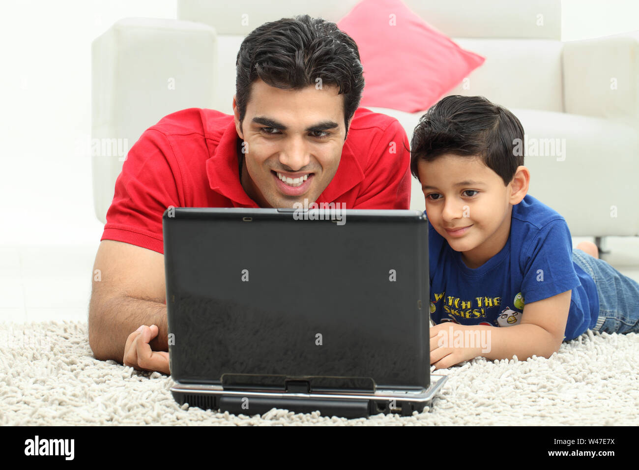 Man assisting his son in using laptop Stock Photo