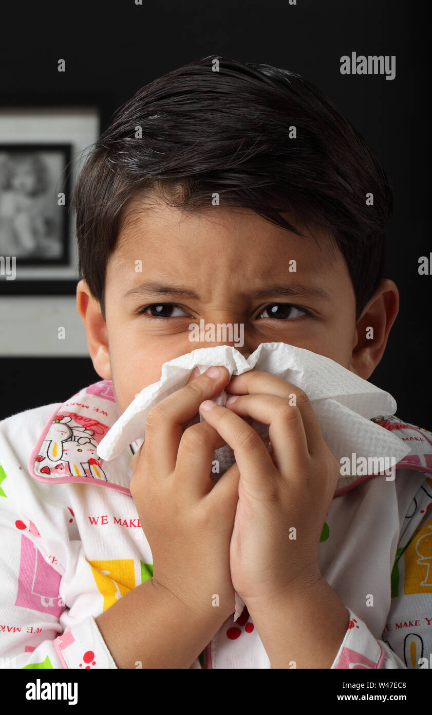 Boy blowing nose with tissue paper Stock Photo Alamy
