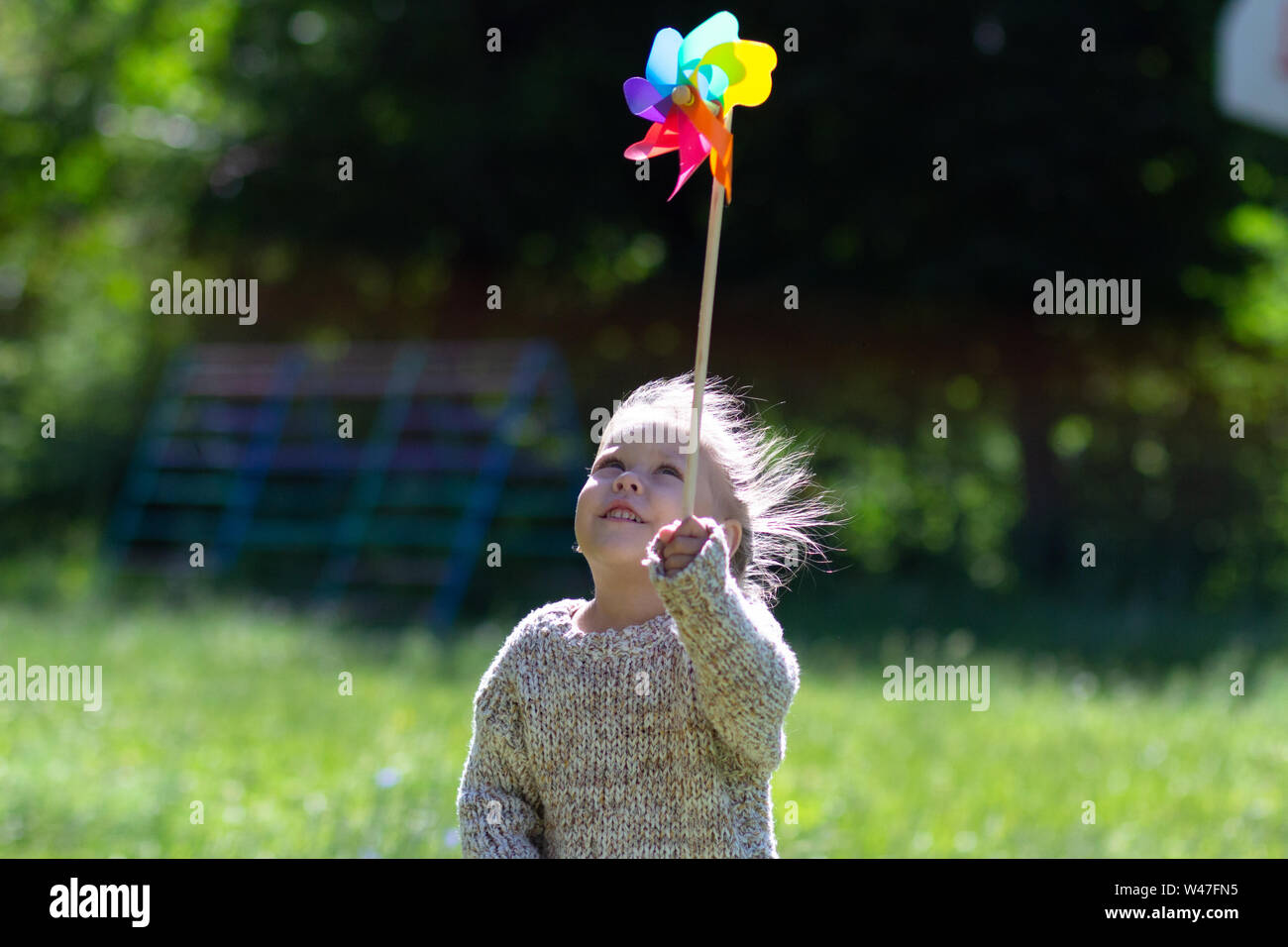 Child with Pinwheel in the summer park looking at toy Stock Photo