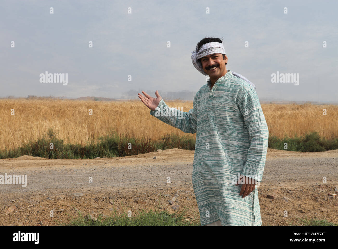 Farmer showing his field and smiling Stock Photo - Alamy