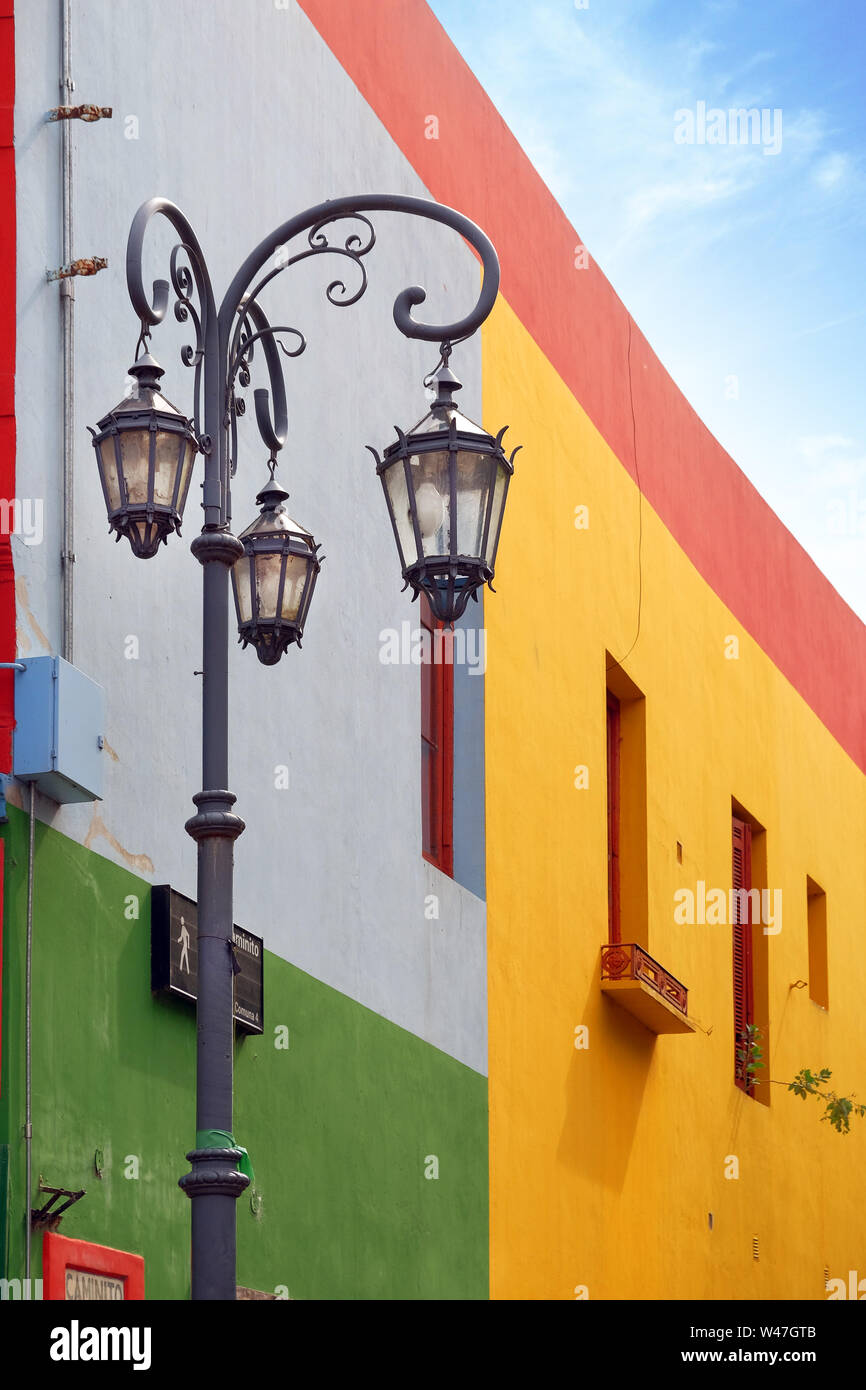 Vertical view of a street lamp and colorful buildings of the Argentinean district La Boca, in Buenos Aires, with old walls against a blue sky. Stock Photo