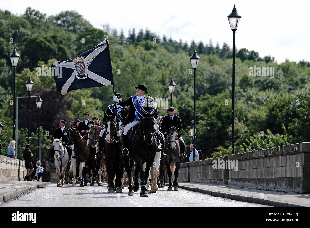 Kelso, SCOTLAND - July 20:    Kelso Civic Week  - Yetholm Ride out, Kelso. Kelso Laddie Mark Henderson carries the Town Flag back across Rennie Bridge, returning to the Town after the ride out to Yetholm Saturday 20 July 2019. Ahead of the 200 strong mounted cavalcade with RHM Sean Hook (2018 KL), Craig Logan (2017 KL).   (Credit: Rob Gray ) Credit: Rob Gray/Alamy Live News Stock Photo