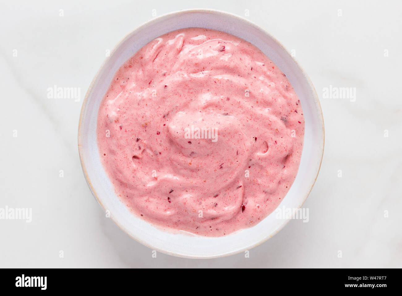 nice cream or smoothie bowl made of frozen bananas and berries on white marble table. healthy breakfast. top view Stock Photo