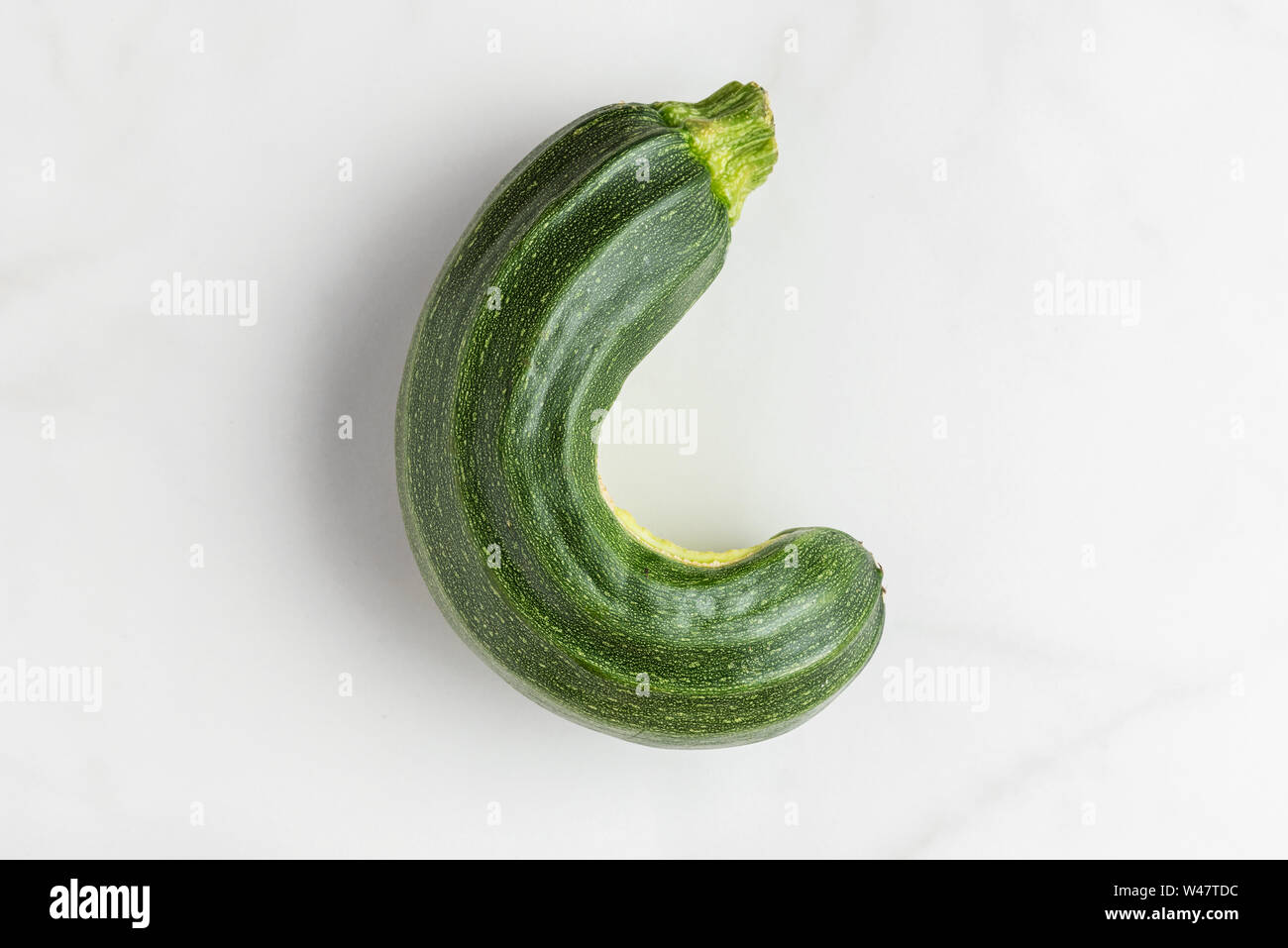 Trendy ugly organic zucchini vegetable from home garden on white marble table. top view. flat lay Stock Photo