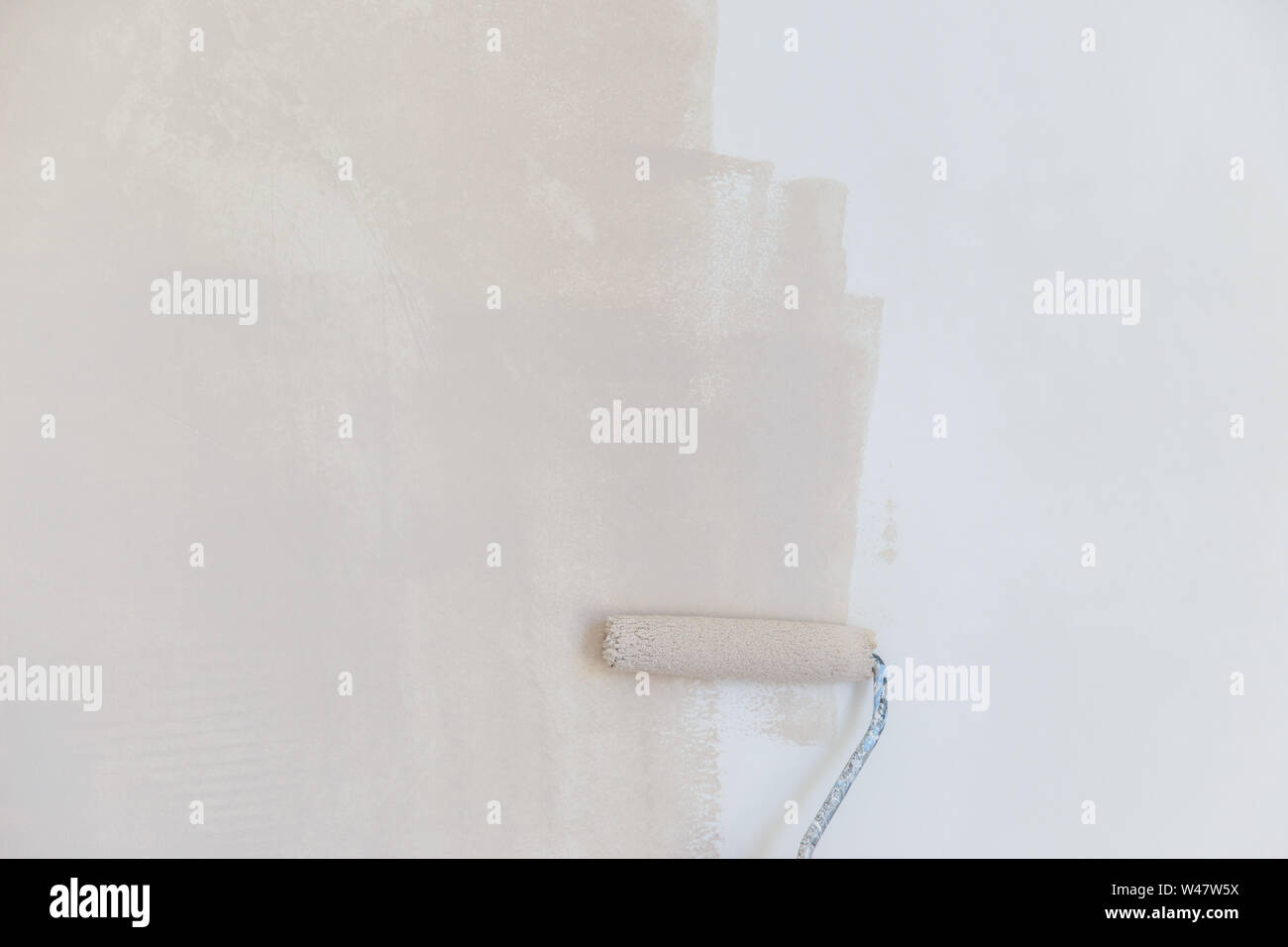 painter hand in white glove painting a wall with paint roller Stock