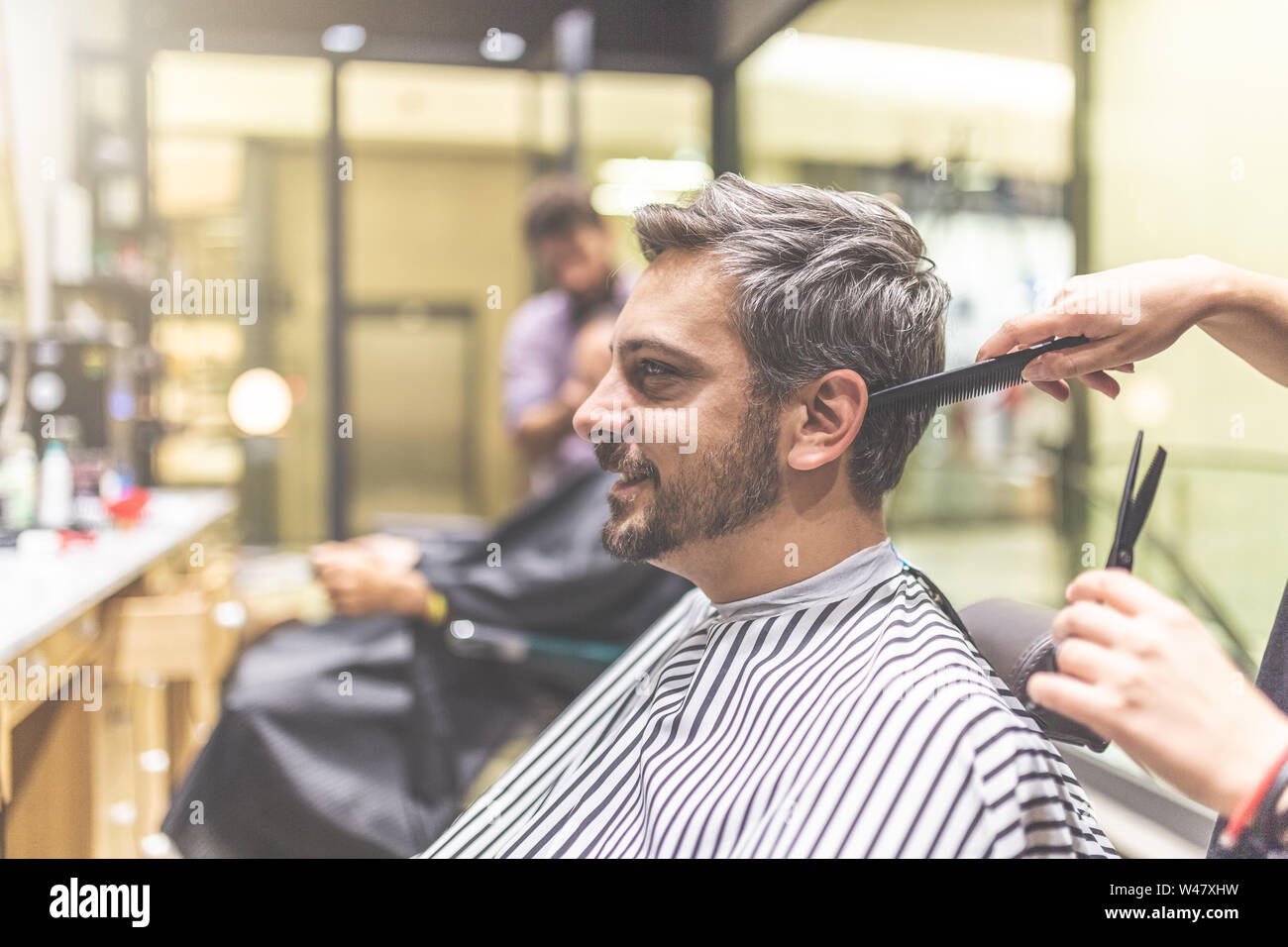 Professional barber styling hair of his client Stock Photo