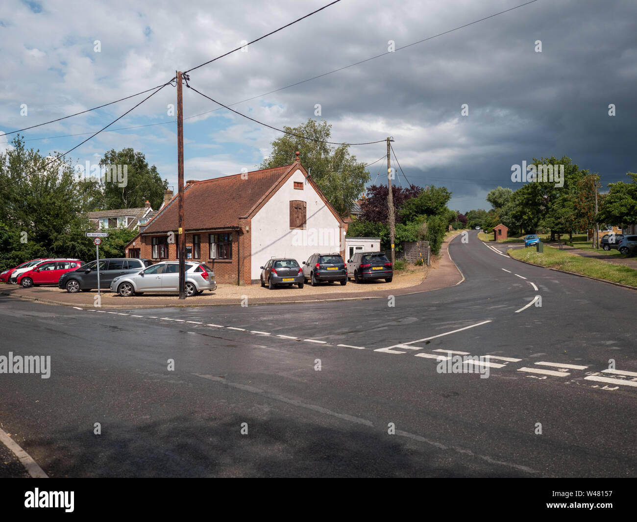 Stoke Holy Cross village hall with rain clouds. Stock Photo