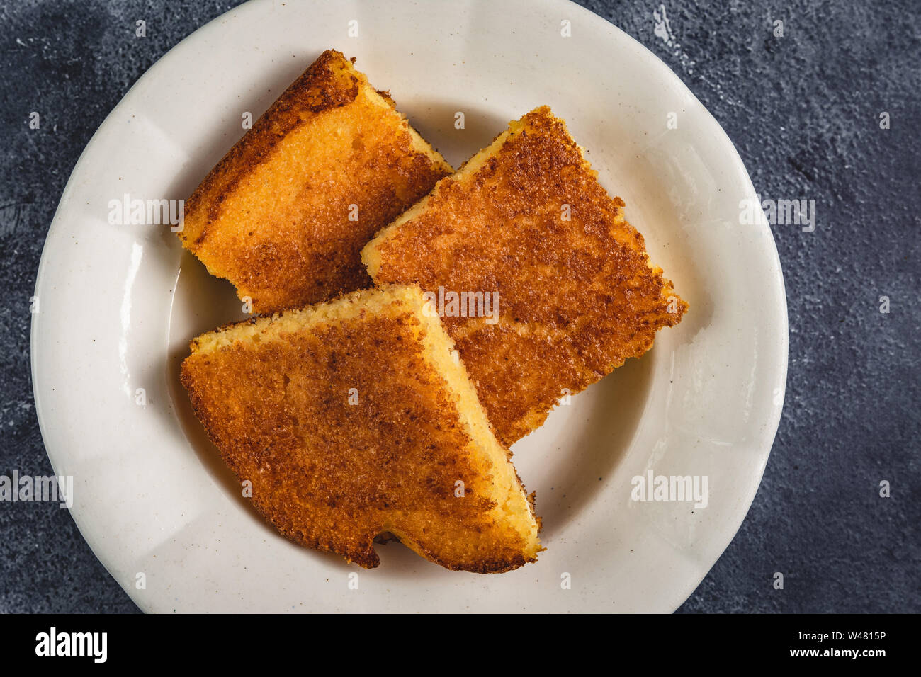 Yellow Corn Bread Squares Slices on Dark Rustic Background Stock Photo