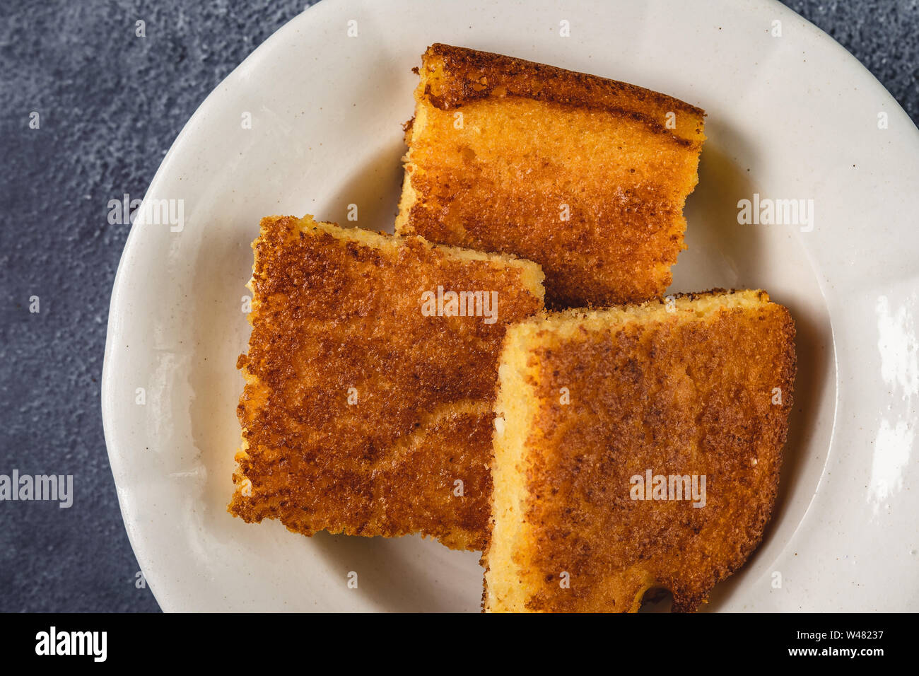Corn Bread Squares Slices in White Plate on Dark Blue Rustic Background Stock Photo
