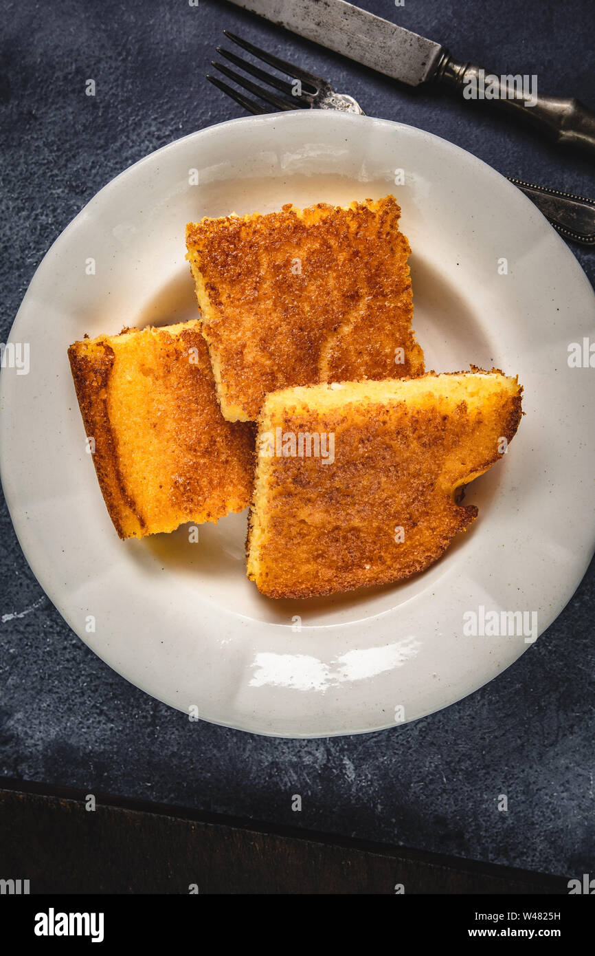 Corn Bread Squares Slices in White Plate on Dark Blue Rustic Background Stock Photo