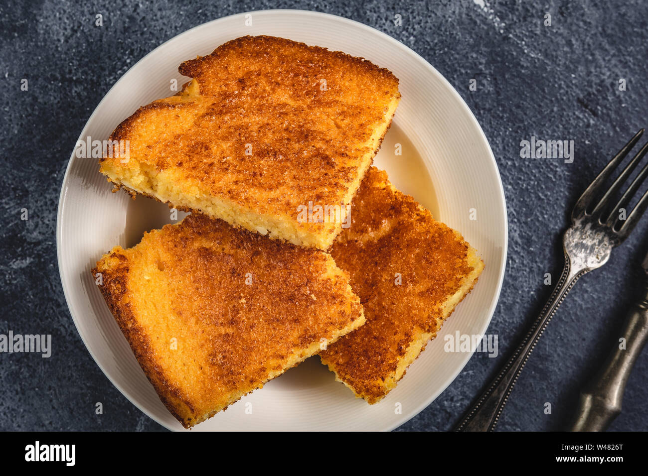 Corn Bread Squares Slices in White Plate on Dark Blue Rustic Background Stock Photo