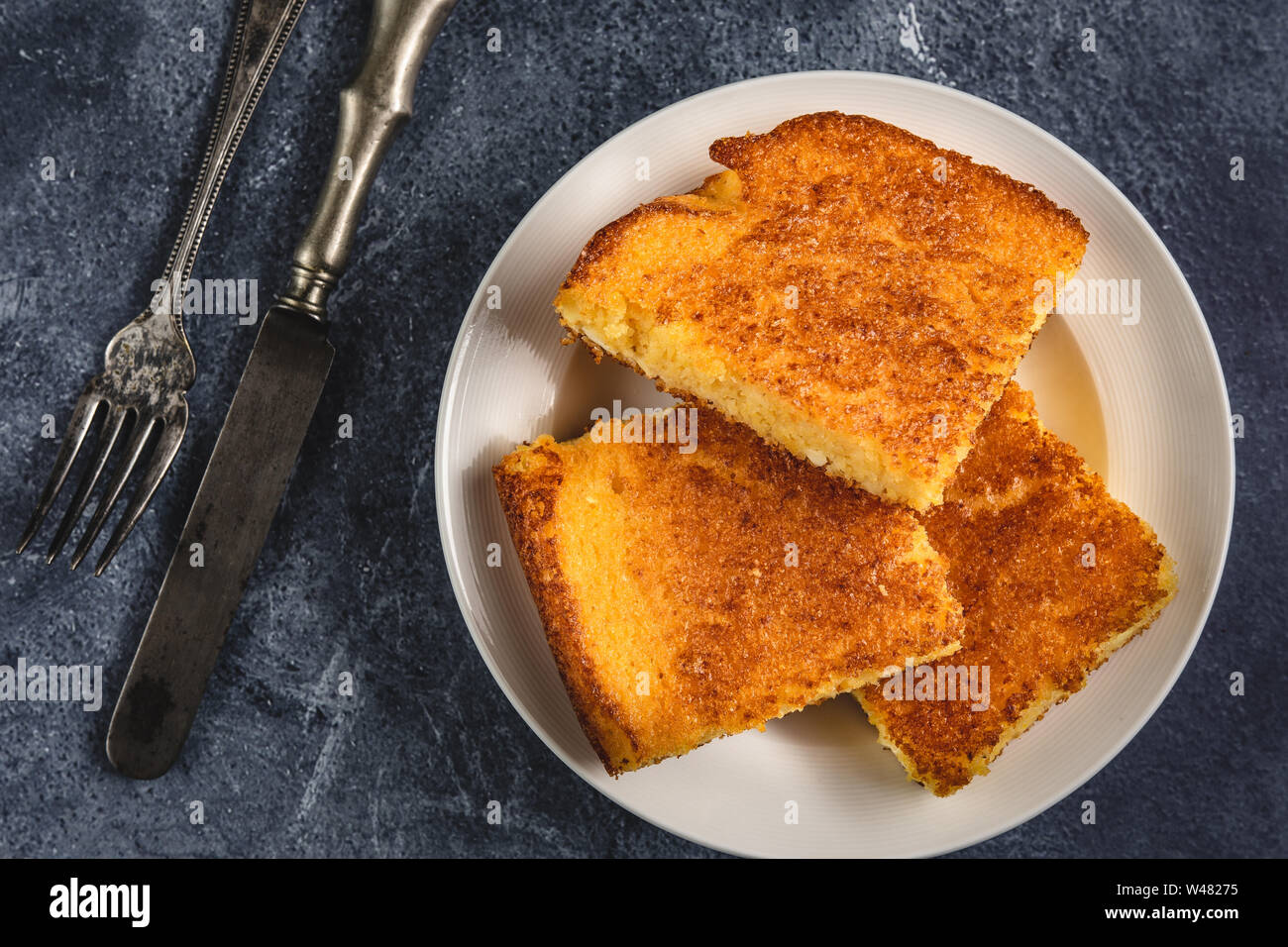 Corn Bread Squares Slices in White Plate on Dark Blue Rustic Background Stock Photo