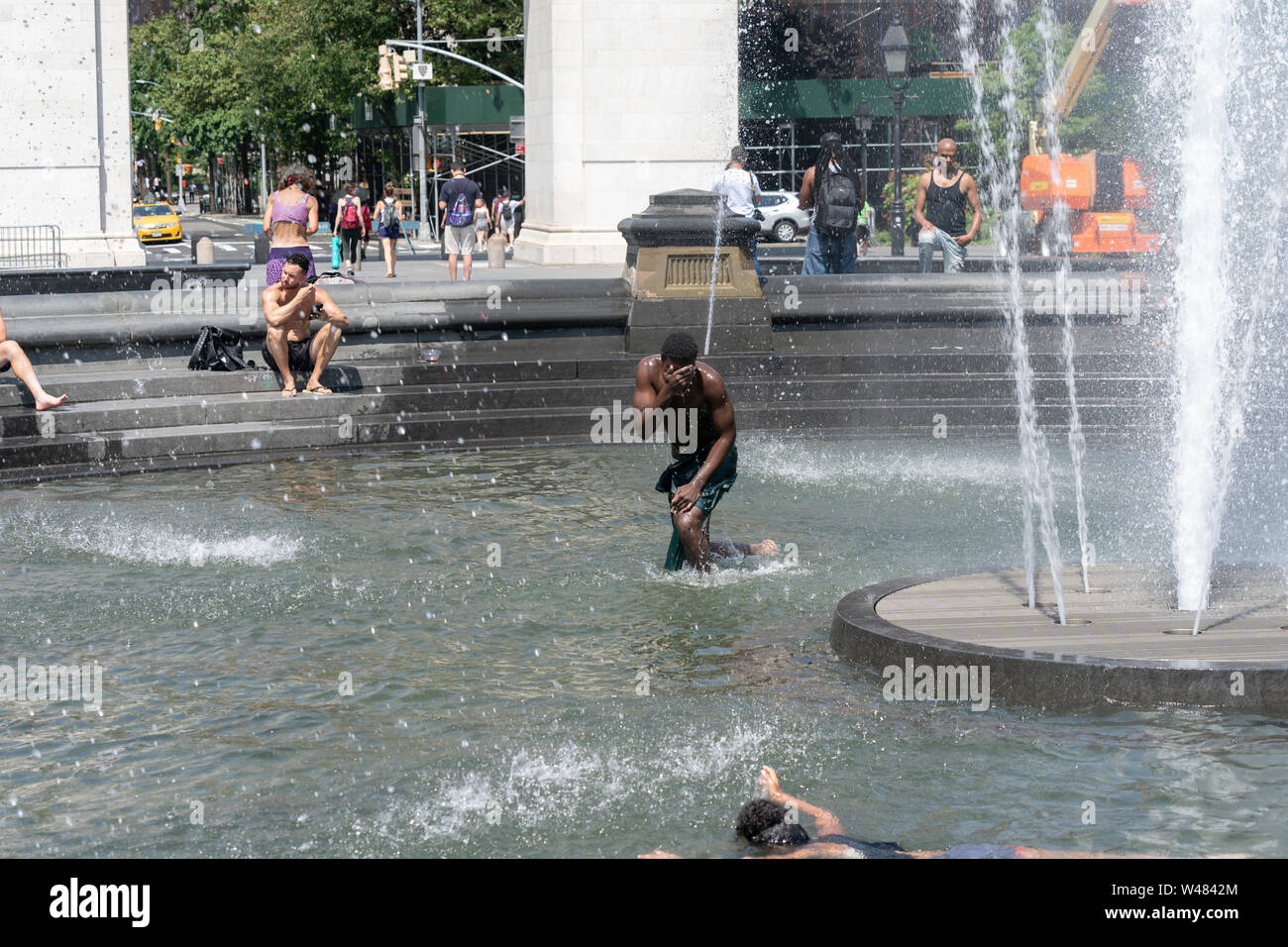 New York, NY - July 20, 2019: New Yorkers cool down in Washington Square fountain as extreme heat wave hit city and temperature reached 105 degrees Fahrenheit (40 degrees Celsius) Stock Photo