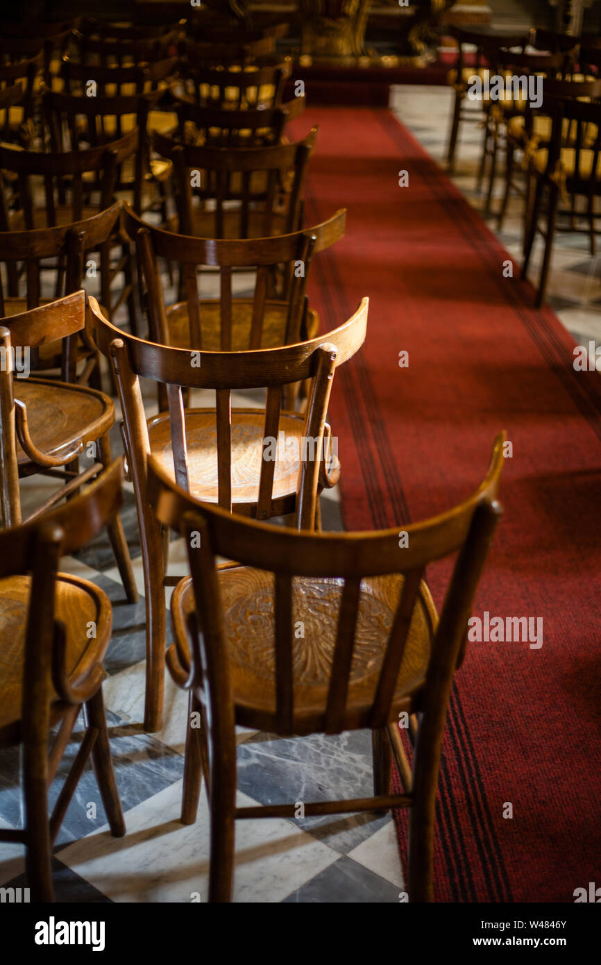 Row of wooden chairs in small chapel in Sicily with light falling on one chair Stock Photo