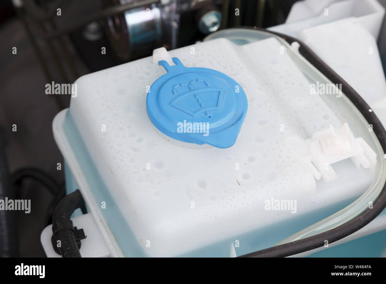 Windscreen washer fluid container and filler cap in a car engine Stock Photo