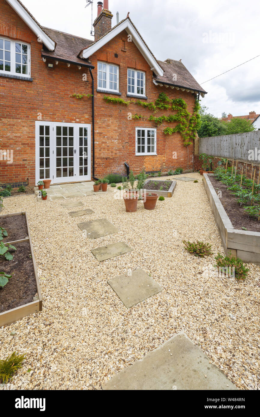 House and garden with a path in gravel leading to french doors through a kitchen courtyard garden Stock Photo