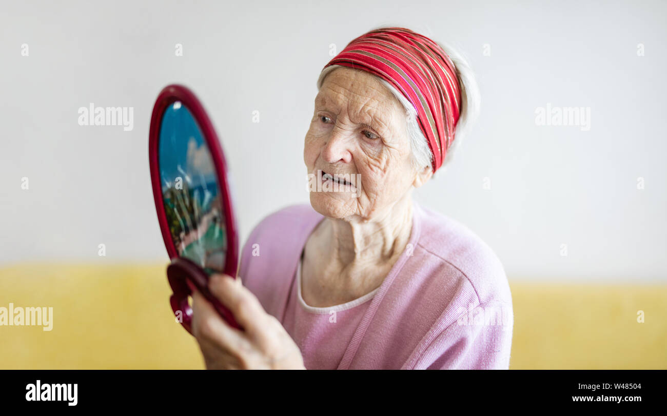 Caucasiasn senior woman looking at herself in mirror Stock Photo