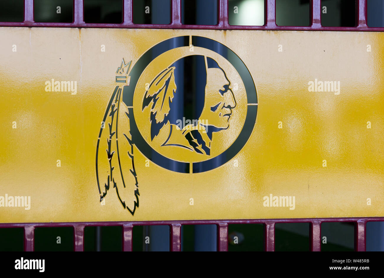 Landover, Maryland, USA. 30th June, 2019. Cutout of Washington Redskins Indian head with trailing feather logo on metal door at Bank of America Gate E — for Loge, Suite, and disabled/handicapped/differently abled guests — at FedEx Field, home stadium of the National Football League's (NFL) controversially named American football team. In July 2019, it was reported that the 32 teams in the league equally shared a record $8.78 billion in national revenue for the past year. Kay Howell/Alamy Stock Photo