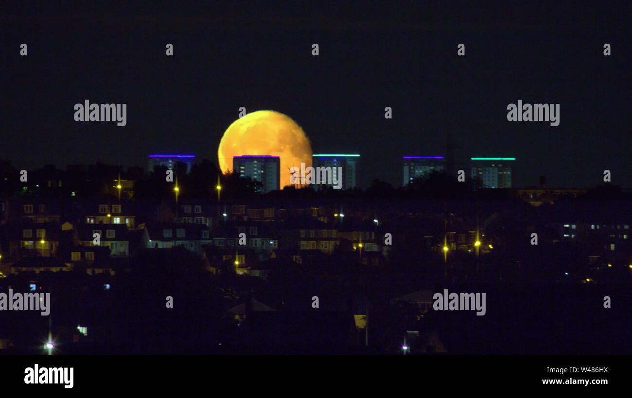 Glasgow, Scotland, UK 20th July, 2019. Moon anniversary rising over the high rises of Maryhill suitably lit up to celebrate the occasion. Gerard Ferry/ Alamy Live News Stock Photo