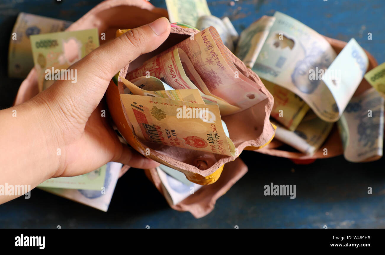 Saving money from broken piggy bank to save up for emergency situation or retirement planning or buy house, many Vietnamese dong banknote Stock Photo