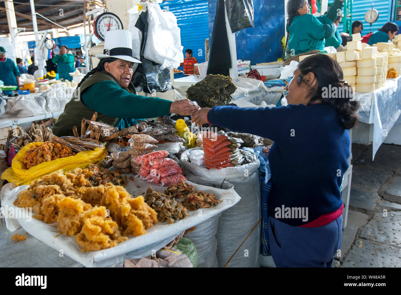 A customer is served by a shopkeeper at a stall in the undercover market place at Cusco in Peru. Stock Photo