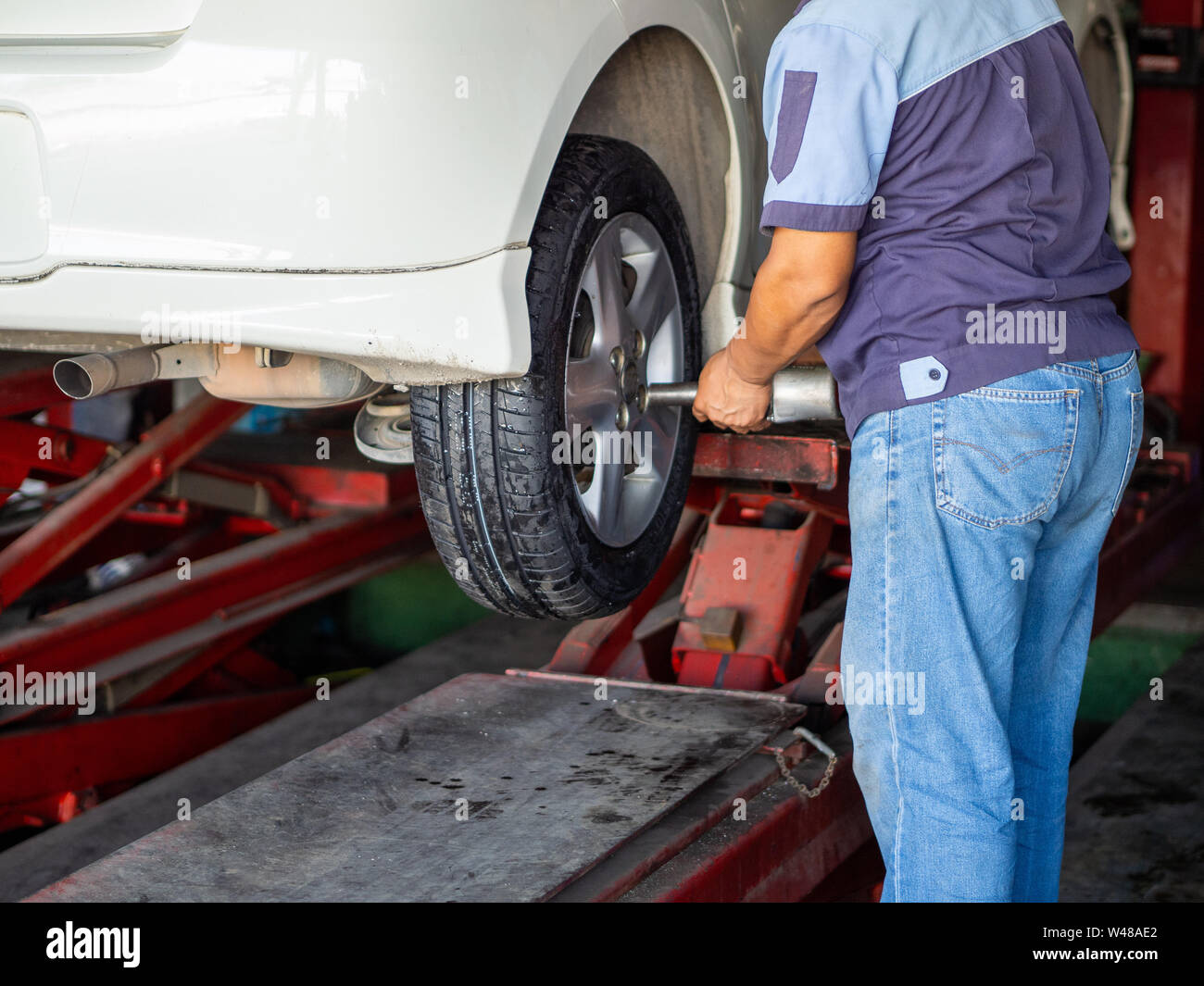 Mechanician changing car wheel in auto repair shop Stock Photo - Alamy