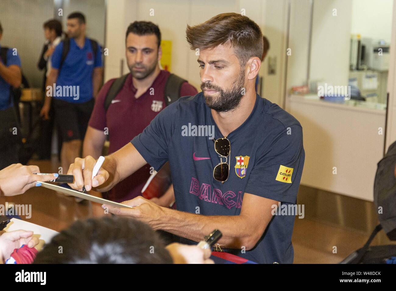 Tokyo, Japan. 21st July, 2019. FC Barcelona player Gerard Pique Bernabeu signs autographs for fans upon his arrival at Tokyo International Airport. FC Barcelona team came to Japan to play in the Rakuten Cup. Many Japanese fans waited with cameras, shirts and autograph boards to welcome the team at the airport. Credit: Rodrigo Reyes Marin/ZUMA Wire/Alamy Live News Stock Photo