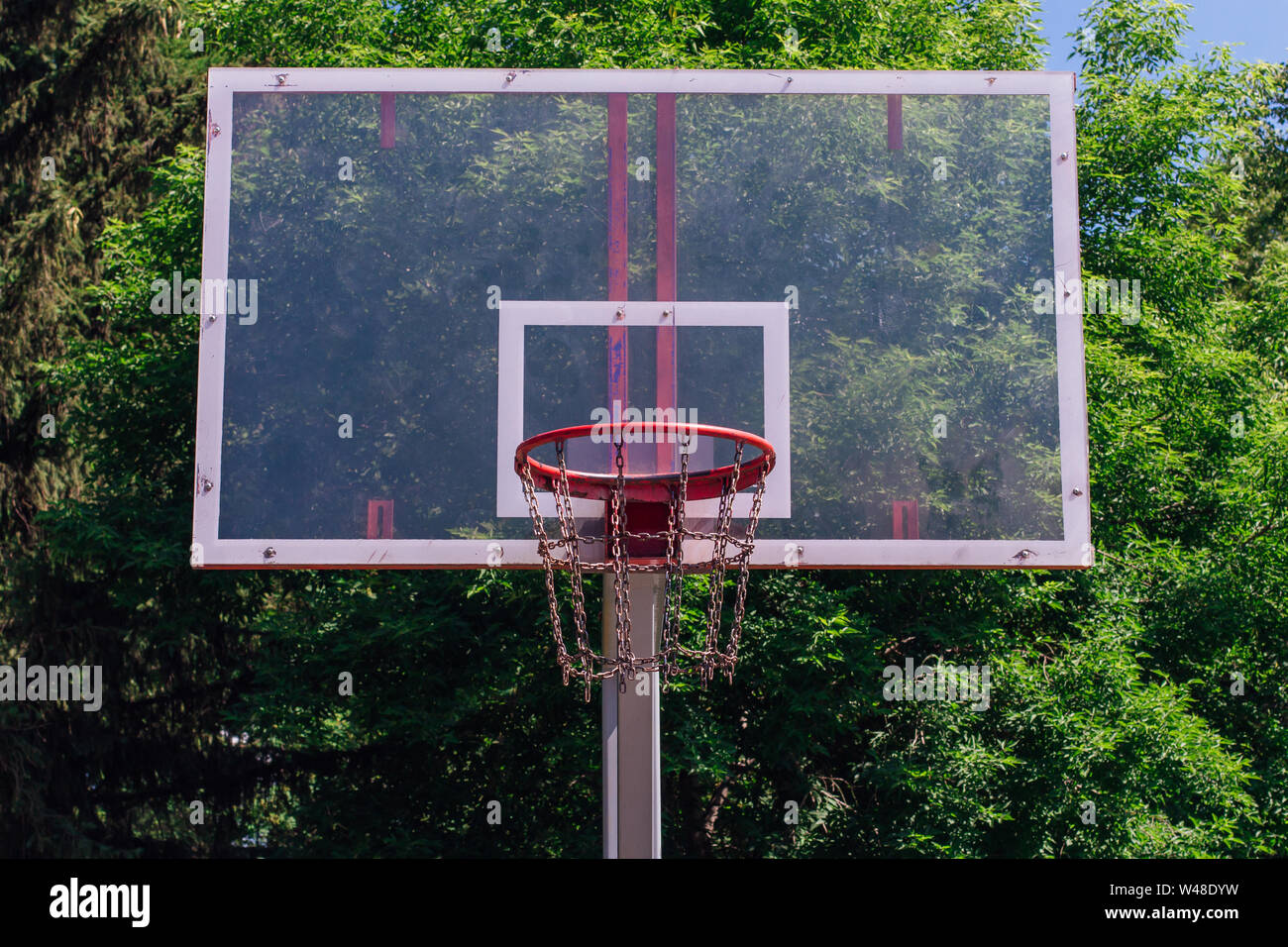 Outdoor basketball ring in front of green trees background. Sport concept  Stock Photo - Alamy