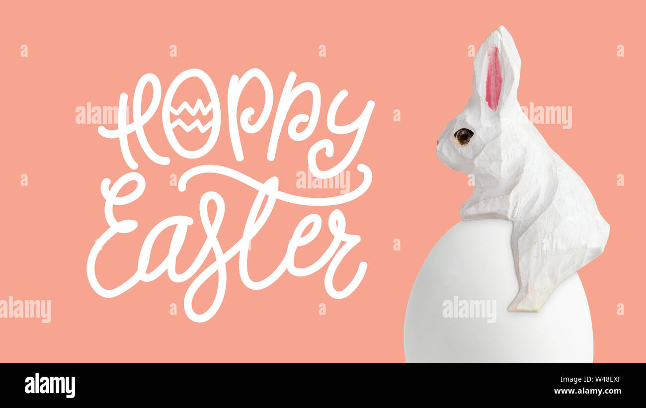 Happy Easter lettering with egg and wood rabbit on orrange background ...