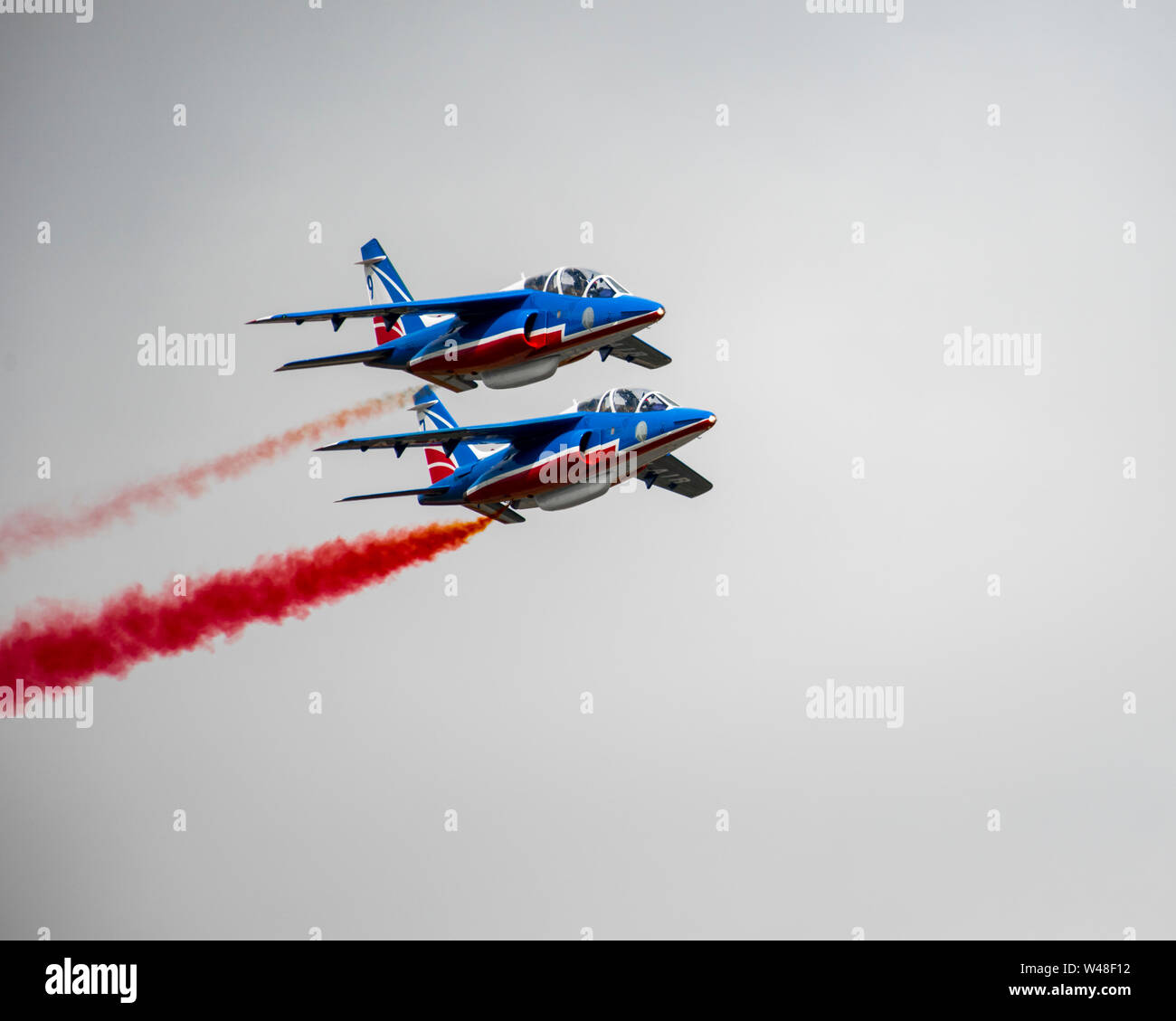 Two members of the French Air Force’s Patrouille de France fly in close formation during the 2019 Royal International Air Tattoo at RAF Fairford, England, July 20, 2019. This year, RIAT commemorated the 70th anniversary of NATO and highlighted the United States' enduring commitment to its European allies. (U.S. Air Force photo by Tech Sgt. Aaron Thomasson) Stock Photo