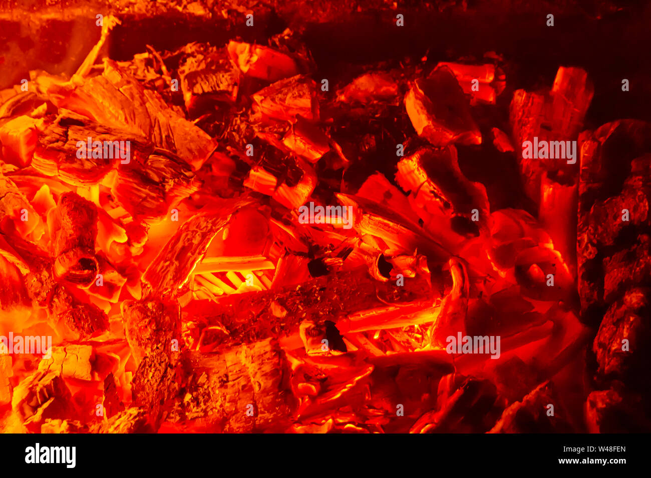 Wallpaper with a bright fire inside the brazier. Flame of fire. Preparation for cooking barbecue, kebabs. Hot coal with lights. Stock Photo