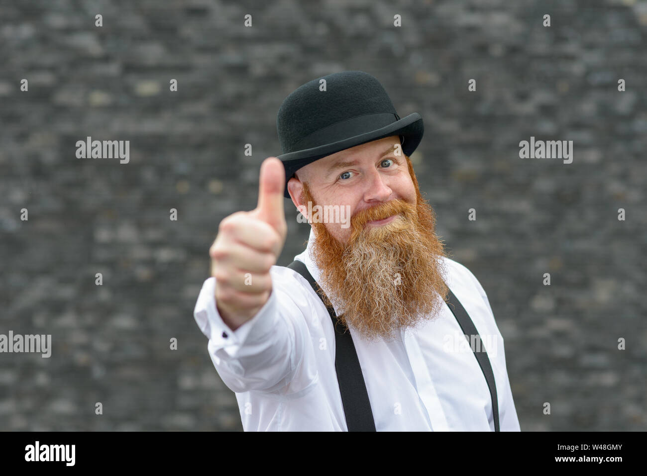 Motivated gleeful man with bushy red beard in retro bowler hat and