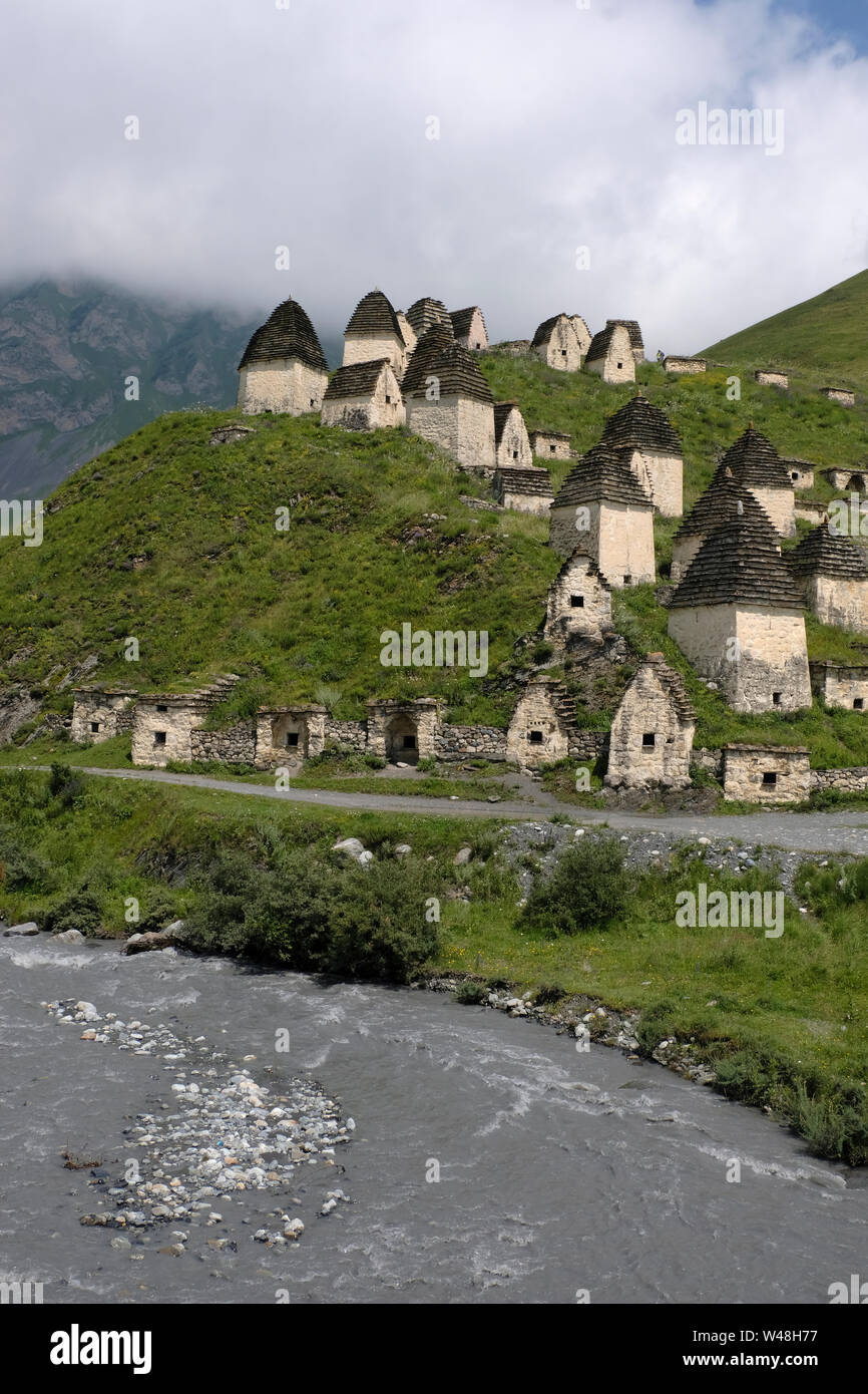View of tombs and crypts of the Alanian necropolis dating back to the 12th century outside the village of Dargavs known locally as the “city of the dead,“ which sits on the slope of a hill overlooking the Fiagdon River in Prigorodny District of the Republic of North Ossetia-Alania in the North Caucasian Federal District of Russia. Stock Photo