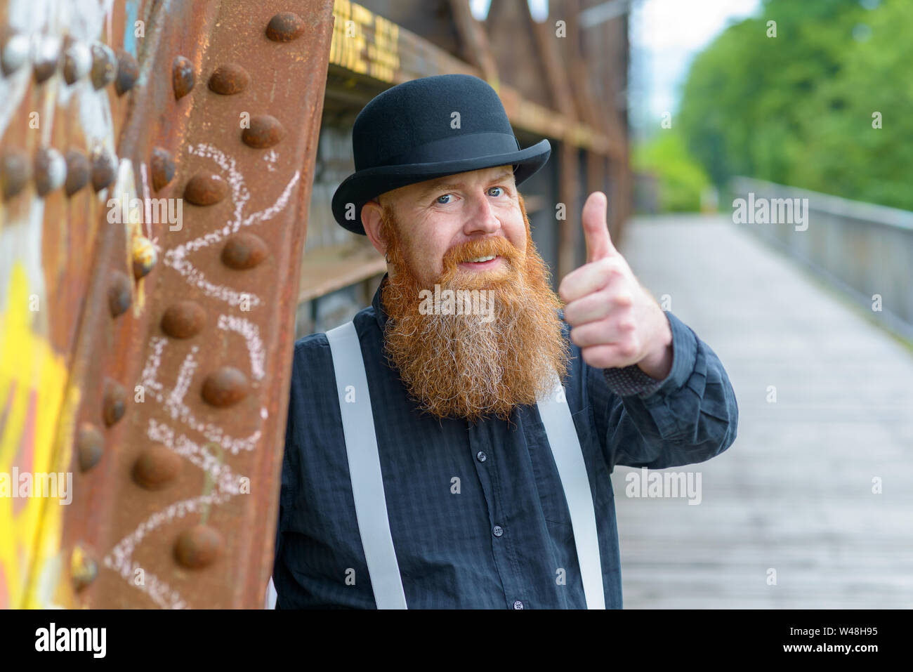 Enthusiastic motivated bearded man in retro style braces and bowler hat