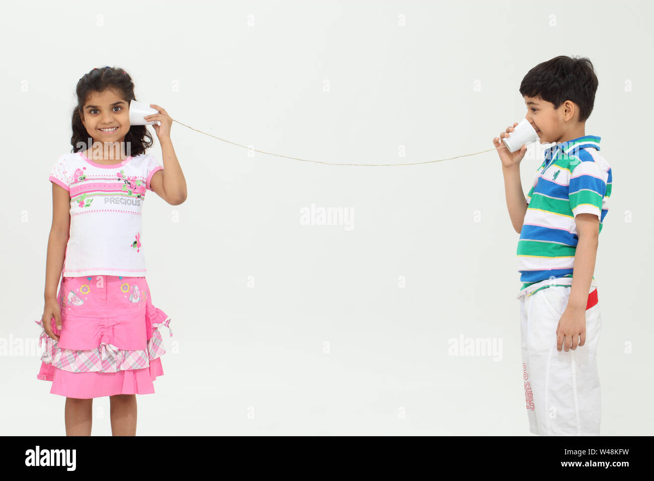 Girl and a boy playing with a tin can phone Stock Photo