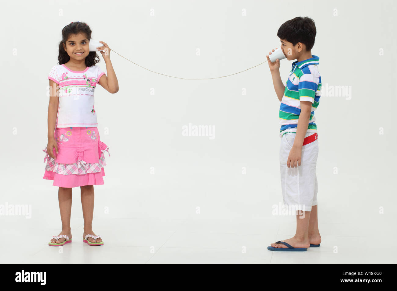 Girl and a boy playing with a tin can phone Stock Photo