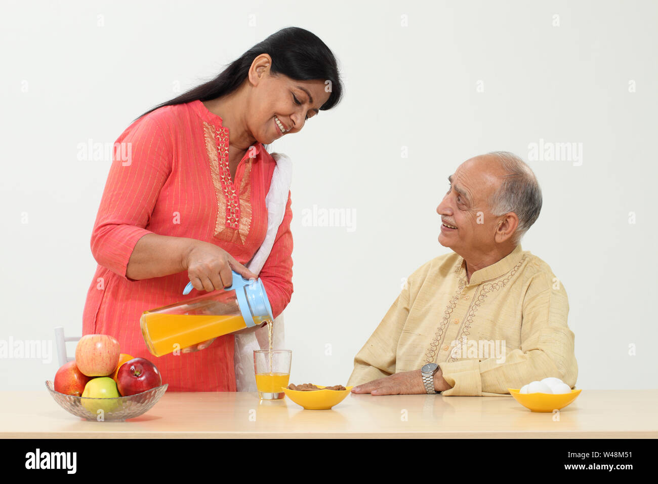 Senior woman pouring orange juice into a glass for her husband Stock