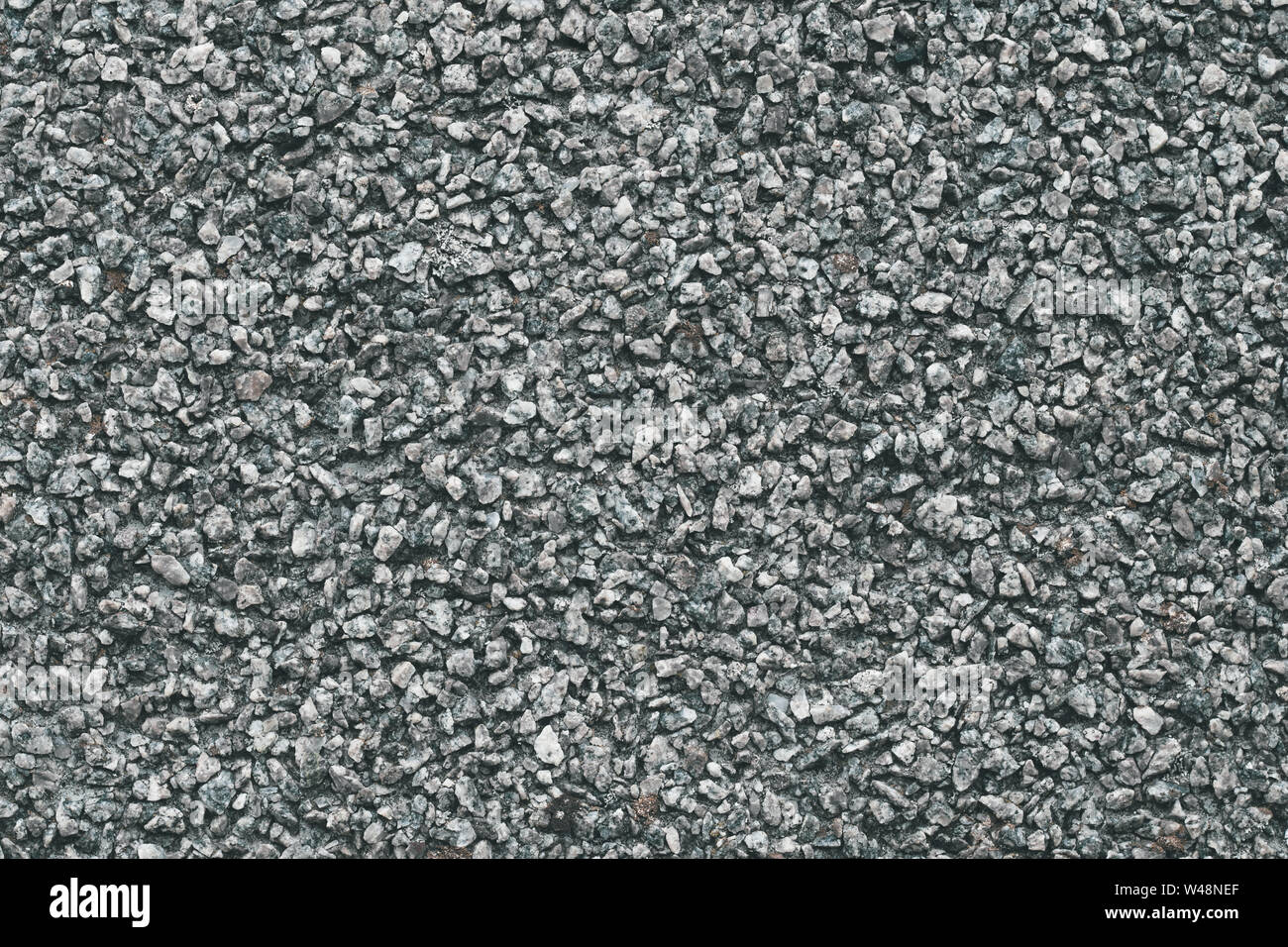Grey stone background. Abstract pattern of gravel. Natural road texture. Rock material. Grunge floor on street. Stock Photo