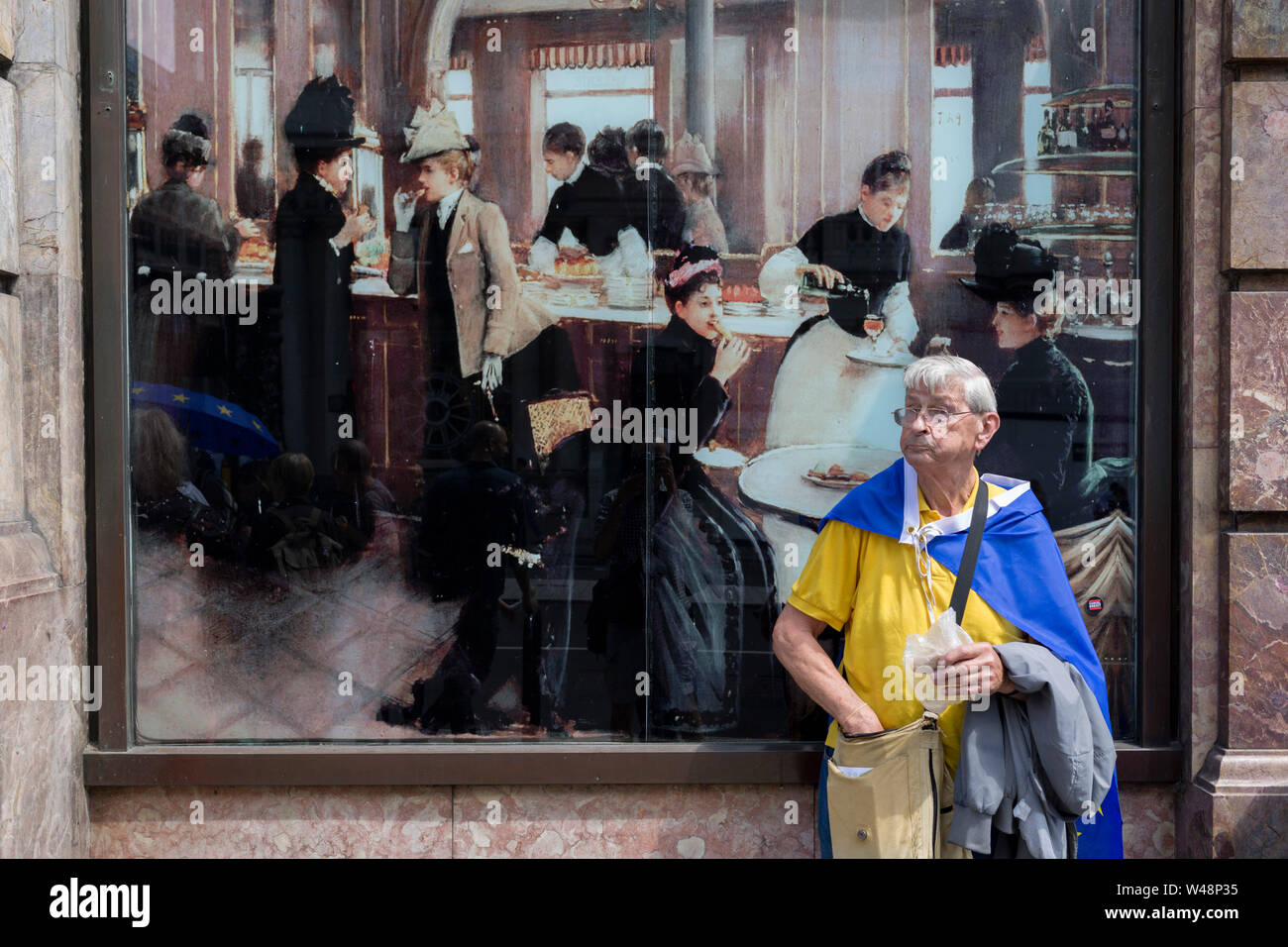 A Brexit protester stops for lunch next to a reproduction of La Patisserie Gloppe by Jean Beraud. Days before the new leader of the Conservative Party and next Prime Minister of the UK is elected by its members (and expected to be Boris Johnson), the last weekend of Theresa May's unsuccessful Brexit from the European Union saw a March for Change protest with pro-EU Remainers marching through the capital demanding an end to Brexit and a No to a Johnson PM, on 20th July 2019, in London, England. Stock Photo